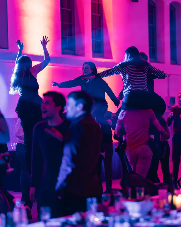 Convives qui dansent sous les lumières roses à la fin d'un banquet