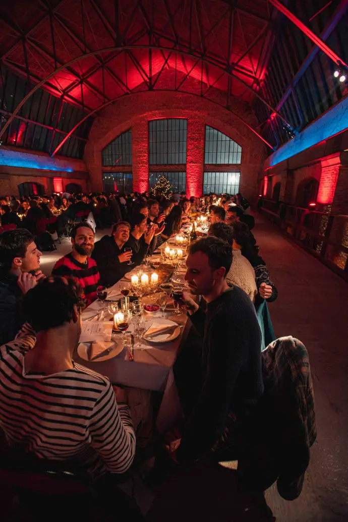 Convives attablés dans une halle aux lumières rouges et bleues